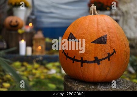 Jack o lanterne avec visage effrayant dessiné sur une souche en bois près de l'entrée de la maison décorée pour la fête traditionnelle d'Halloween Banque D'Images