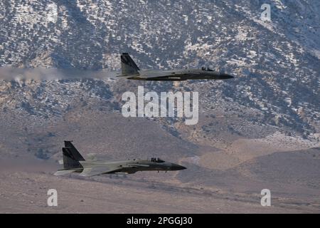 Lone Pine, CA - 10 novembre 2022 : deux chasseurs F-15 de l'USAF volent au niveau inférieur sur le sentier de bas niveau Sidewinder-D avec des montagnes enneigées dans le b Banque D'Images