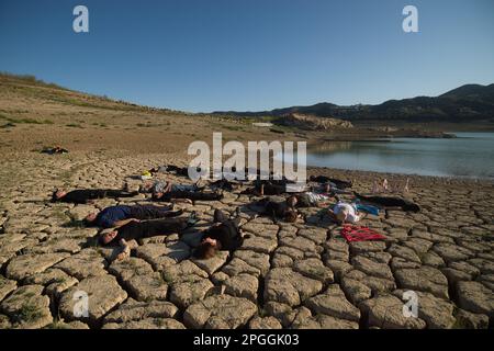 Les militants des droits de l'homme et de l'environnement sont vus sur un terrain fissuré lors d'une manifestation contre le changement climatique, organisée par Amnesty International. Pour marquer la Journée internationale de l'eau, des militants d'Amnesty International, ainsi que plusieurs organisations environnementales, ont dénoncé le changement climatique et ses effets sur les droits de l'homme dans le monde entier par une performance qui représente la mort symbolique du réservoir de la Viñuela. Le réservoir de Viñuela, qui fournit de l'eau aux municipalités près de la région d'Axarquia, est à un niveau d'eau minimal en raison de la grave sécheresse dans la province. (Photo Banque D'Images