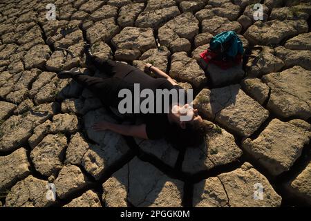 Une militante de l'environnement est vue sur le terrain craqué alors qu'elle participe à une manifestation contre le changement climatique, organisée par Amnesty International. Pour marquer la Journée internationale de l'eau, des militants d'Amnesty International, ainsi que plusieurs organisations environnementales, ont dénoncé le changement climatique et ses effets sur les droits de l'homme dans le monde entier par une performance qui représente la mort symbolique du réservoir de la Viñuela. Le réservoir de Viñuela, qui fournit de l'eau aux municipalités près de la région d'Axarquia, est à un niveau d'eau minimal en raison de la grave sécheresse dans la province. (P Banque D'Images