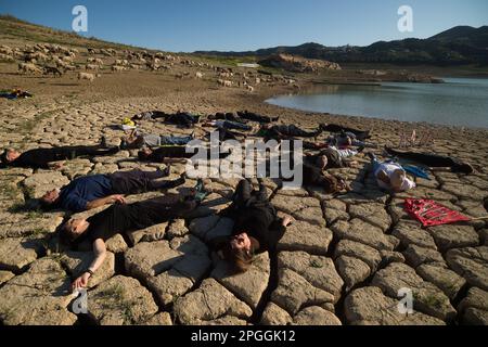 Les militants des droits de l'homme et de l'environnement sont vus sur un terrain fissuré lors d'une manifestation contre le changement climatique, organisée par Amnesty International. Pour marquer la Journée internationale de l'eau, des militants d'Amnesty International, ainsi que plusieurs organisations environnementales, ont dénoncé le changement climatique et ses effets sur les droits de l'homme dans le monde entier par une performance qui représente la mort symbolique du réservoir de la Viñuela. Le réservoir de Viñuela, qui fournit de l'eau aux municipalités près de la région d'Axarquia, est à un niveau d'eau minimal en raison de la grave sécheresse dans la province. (Photo Banque D'Images