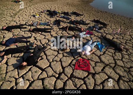 Les militants des droits de l'homme et de l'environnement sont vus sur un terrain fissuré lors d'une manifestation contre le changement climatique, organisée par Amnesty International. Pour marquer la Journée internationale de l'eau, des militants d'Amnesty International, ainsi que plusieurs organisations environnementales, ont dénoncé le changement climatique et ses effets sur les droits de l'homme dans le monde entier par une performance qui représente la mort symbolique du réservoir de la Viñuela. Le réservoir de Viñuela, qui fournit de l'eau aux municipalités près de la région d'Axarquia, est à un niveau d'eau minimal en raison de la grave sécheresse dans la province. Banque D'Images