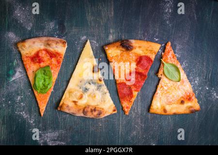 Assortiment de tranches de pizza. Margherita, pepperoni, fromage pizza quatre. Vue d'en haut. Différents types de pizza sur la table en bois texturé Banque D'Images