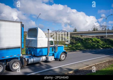 Tracteur semi-remorque classique américain à capot industriel blanc et bleu avec béquet de toit transportant des marchandises congelées dans une semi-remorque réfrigérée Banque D'Images