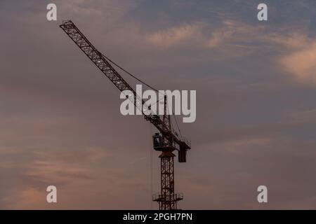 silhouette d'une grue de tour sur un chantier de construction au crépuscule avec de belles couleurs riches sur le fond du ciel. Banque D'Images