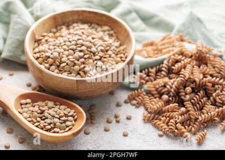 Pâtes de lentilles vertes fusilli sur fond de béton gris. Un bol de pâtes crues et de lentilles vertes. Pâtes sans gluten. Banque D'Images