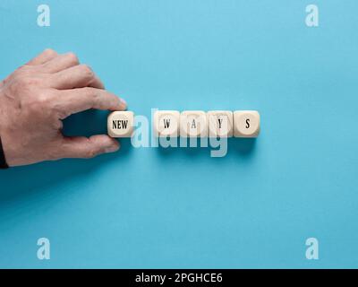 Nouvelles possibilités, méthodes, stratégies ou approches. La main masculine arrange les cubes en bois avec le mot nouvelles manières. Banque D'Images