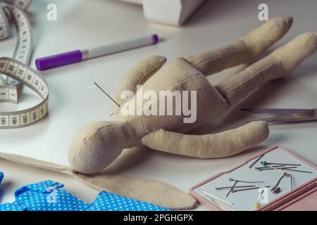 Jouet de lapin farci avec aiguilles couchée sur la table. Tricoter hobby et affaires. Petit jouet de lièvre à côté de ruban de mesure de couture et de la couture. Faites-le Banque D'Images