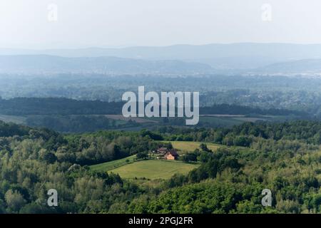 Maison rurale entourée d'une forêt luxuriante, des couches de colline dans la brume Banque D'Images