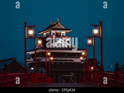 Un pont rouge illuminé avec le château de Kiyosu en arrière-plan. Préfecture d'Aichi, Japon. Banque D'Images