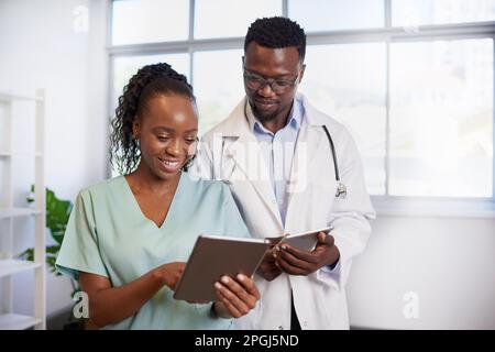 Le médecin noir se tourne vers l'infirmière tout en discutant de la note du patient sur la tablette numérique Banque D'Images