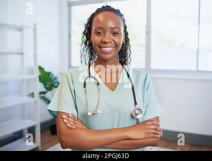 Portrait d'une jeune femme noire médecin, les bras pliés en souriant dans le bureau moden Banque D'Images