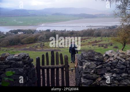 Lone Man marchant devant la porte en bois dans le mur de pierre menant à Red Hills Wood d'Arnside Knott à Arnside, Cumbria, Angleterre, Royaume-Uni. Banque D'Images