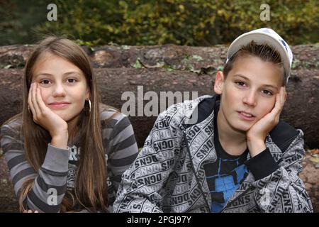 les têtes reposant sur les mains des jeunes frères et sœurs s'ennuient ensemble dans les bois Banque D'Images