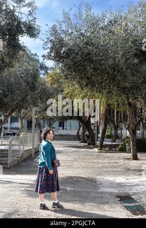 Portrait d'une jeune fille brune de vingt-cinq ans vêtue d'une robe bleue vintage avec un motif et un chemisier vert avec un petit sac à main Banque D'Images