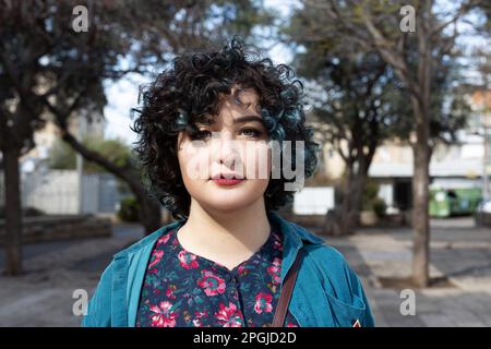 Portrait d'une jeune fille brune de vingt-cinq ans vêtue d'une robe bleue vintage avec un motif et un chemisier vert avec un petit sac à main Banque D'Images