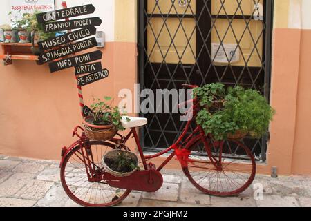 Vélo décoratif en face du centre d'information touristique, avec des flèches pointant vers différentes attractions à Gallipoli, Italie Banque D'Images