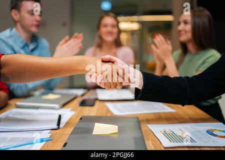 Gros plan sur un homme d'affaires caucasien et une femme d'affaires africaine méconnaissables qui se font les mains lors d'une réunion de groupe, avec des hommes d'affaires variés Banque D'Images
