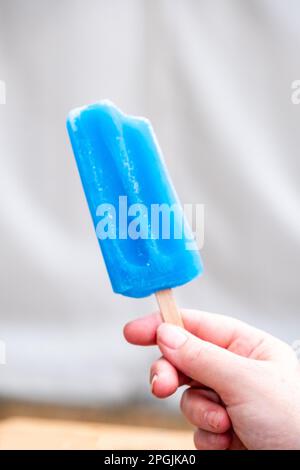Une main de womans tenant une glace bleue partiellement grignotée à la tête d'un village. Banque D'Images