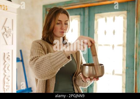 Jeune femme jouant sur un chant tibetian Bowl.relaxation et méditation.thérapie sonore, médecine alternative.pratiques de guérison bouddhiste.espace de dégagement de l'énergie négative.foyer sélectif,gros plan. Banque D'Images