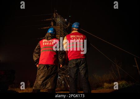 ZHENJIANG, CHINE - LE 22 MARS 2023 - les travailleurs de l'électricité font braver la pluie pour modifier le fil de masse de la Zhenline 5 de 220 kV traversant le chemin de fer à grande vitesse Banque D'Images