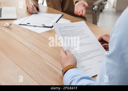 Homme lisant le contrat d'emploi à la table au bureau, clôture. Signature du contrat Banque D'Images