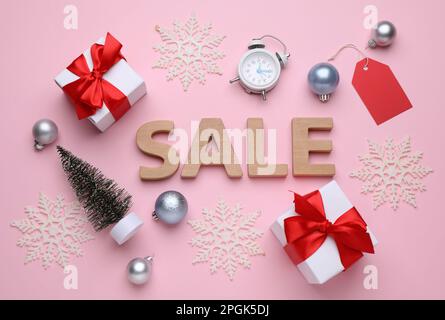 Vente de mots faite de lettres en bois, boîtes-cadeaux, réveil et décorations de Noël sur fond rose, plat Banque D'Images