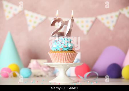 21th anniversaire. Délicieux cupcake avec des bougies en forme de nombre pour venir de la fête d'âge sur table blanche Banque D'Images