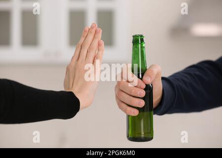 Femme refusant de boire de la bière dans la cuisine, en gros plan. Traitement de la dépendance à l'alcool Banque D'Images