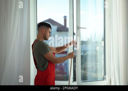 Un employé pose une bande de traction en caoutchouc sur la fenêtre à l'intérieur Banque D'Images