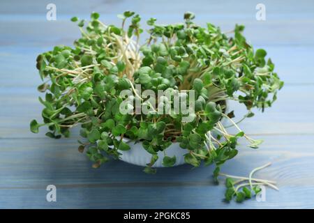 Microverts de radis frais dans un bol sur une table en bois bleu clair Banque D'Images