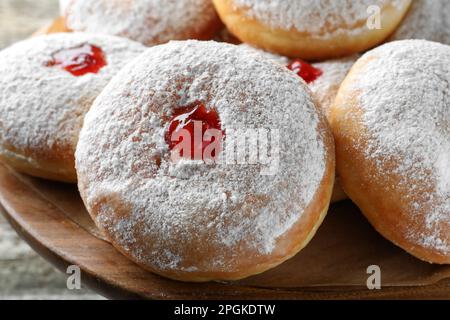 Délicieux beignets avec gelée et sucre en poudre sur un présentoir à pâtisseries en bois, gros plan Banque D'Images