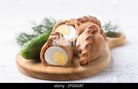 Tourtes traditionnelles russes de seigle avec oeuf, kokurki, sur fond gris clair avec concombre et herbes. Délicieux en-cas et plats faits maison Banque D'Images