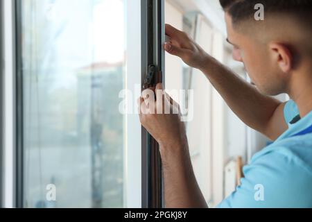 Homme mettant la bande de traction en caoutchouc sur la fenêtre à l'intérieur, se concentrer sur les mains Banque D'Images