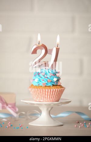 21th anniversaire. Délicieux cupcake avec des bougies en forme de nombre pour venir de la fête d'âge sur la table Banque D'Images