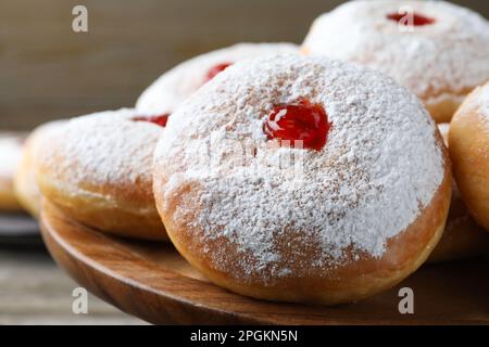 Délicieux beignets avec gelée et sucre en poudre sur un présentoir à pâtisseries en bois, gros plan Banque D'Images