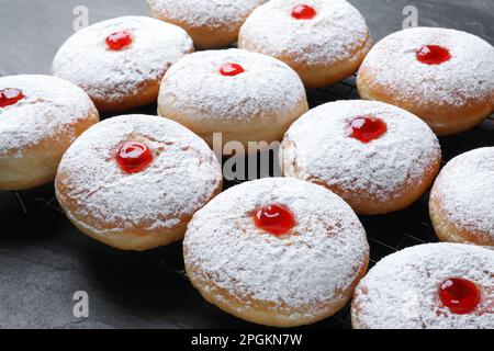 Beaucoup de délicieux beignets avec gelée et sucre en poudre sur table noire Banque D'Images