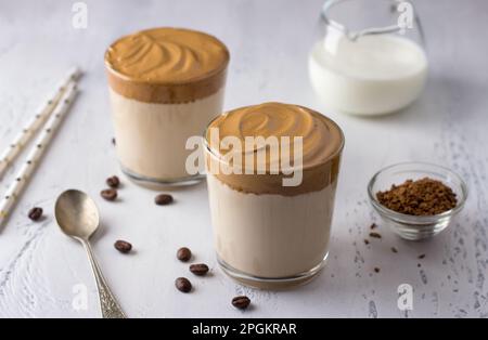 Deux verres avec café Dalgona, cocktail froid avec mousse de café fouettée, boisson tendance populaire sur un fond texturé clair Banque D'Images
