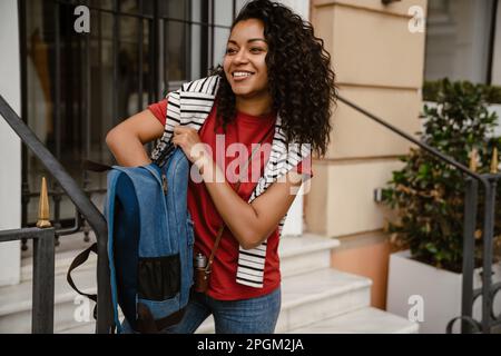Jeune femme noire souriant en se tenant debout près du bâtiment à l'extérieur Banque D'Images