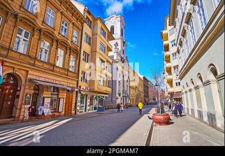 BUDAPEST, HONGRIE - 22 FÉVRIER 2022 : logement dense de la rue Vaci avec un bâtiment de l'église St Michael de la ville intérieure avec une tour d'horloge, le 22 février à Budapes Banque D'Images