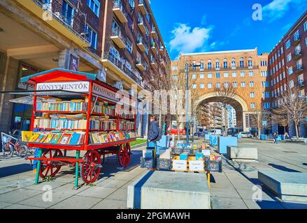 BUDAPEST, HONGRIE - 22 FÉVRIER 2022 : kiosque de livre de style vintage sur la place Imre Madach avec des maisons de Madach en brique rouge avec une grande colonnade et un col voûté Banque D'Images