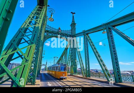 Le tramway jaune, qui monte sur le pont de la liberté avec de beaux éléments en métal vert vif, Budapest, Hongrie Banque D'Images