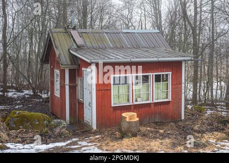 Petite cabane en bois d'ocre rouge sur l'île de Kuusiluoto, le jour de printemps est brumeux. Helsinki, Finlande. Banque D'Images