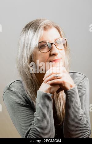 Portrait d'une belle femme portant des lunettes. Isolé sur fond gris. Banque D'Images