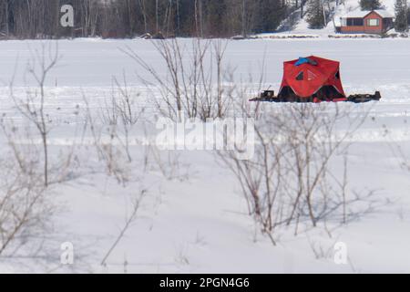 tente rouge de pêche sur glace sur un lac gelé Banque D'Images