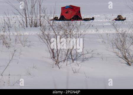 tente rouge de pêche sur glace sur un lac gelé Banque D'Images
