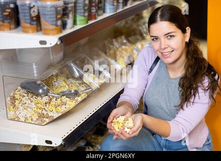 Femme tenant une poignée de nourriture sèche pour chien dans le magasin d'animaux de compagnie Banque D'Images