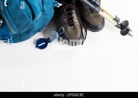 Gros plan sur un sac à dos, des chaussures de randonnée, des bâtons et une boussole sur fond blanc avec espace de copie Banque D'Images