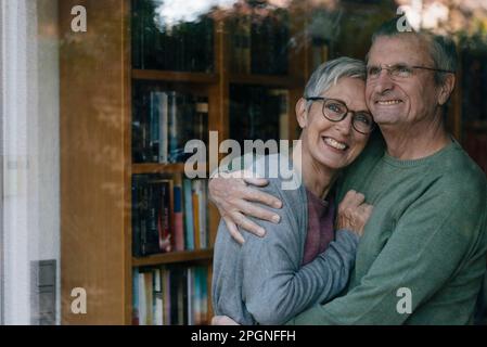 Portrait of happy senior couple hugging derrière la vitre Banque D'Images