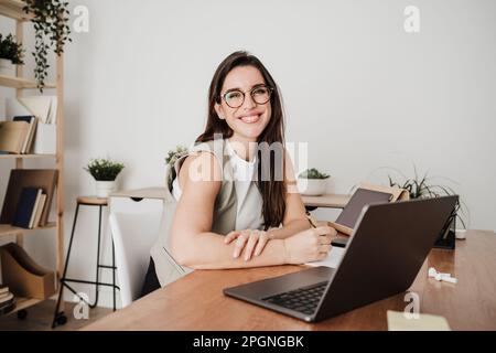 Bonne femme d'affaires assise devant un ordinateur portable au bureau Banque D'Images